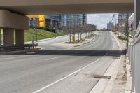 an empty street below a bridge over the highway, where there are benches and signs to the right