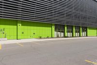 there is a parking lot next to a building with yellow markings on it and some green doors