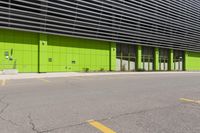 there is a parking lot next to a building with yellow markings on it and some green doors