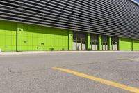 there is a parking lot next to a building with yellow markings on it and some green doors