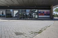 a person sitting at the bench in front of a mall that is empty of people