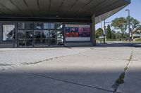 a person sitting at the bench in front of a mall that is empty of people