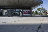 a person sitting at the bench in front of a mall that is empty of people