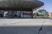 a person sitting at the bench in front of a mall that is empty of people