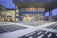 the entrance of a glass building on a very busy day that is empty at night