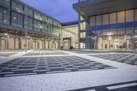 the entrance of a glass building on a very busy day that is empty at night