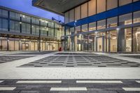 the entrance of a glass building on a very busy day that is empty at night