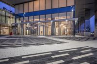 the entrance of a glass building on a very busy day that is empty at night