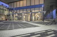 the entrance of a glass building on a very busy day that is empty at night