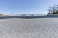 an empty road on a sunny day with blue sky above it and a bridge over the street in the distance