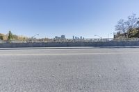 an empty road on a sunny day with blue sky above it and a bridge over the street in the distance