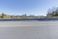 an empty road on a sunny day with blue sky above it and a bridge over the street in the distance