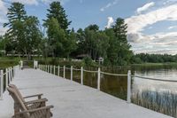 the dock has a wooden bench on it near the water and a bridge with a white fence