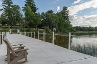 the dock has a wooden bench on it near the water and a bridge with a white fence