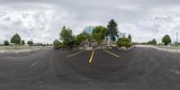 an image from a fisheye lens of a park in front of a building and trees