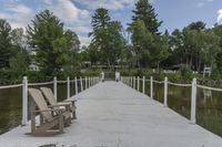 a wooden chair sits on the end of a pier next to water and trees around it