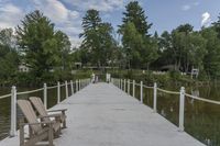 a wooden chair sits on the end of a pier next to water and trees around it