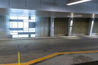 a empty parking garage with some empty floor space and a long building entrance way with no windows