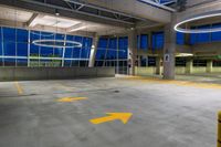 a view of an empty parking garage at night, from the street level side with multiple yellow arrows pointing up