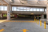 large open parking area with large circular light on top of the roof and yellow painted arrows on the floor