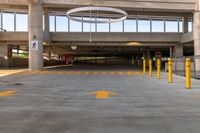 large open parking area with large circular light on top of the roof and yellow painted arrows on the floor