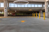 large open parking area with large circular light on top of the roof and yellow painted arrows on the floor