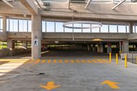 large open parking area with large circular light on top of the roof and yellow painted arrows on the floor