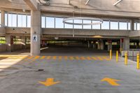 large open parking area with large circular light on top of the roof and yellow painted arrows on the floor