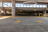 large open parking area with large circular light on top of the roof and yellow painted arrows on the floor