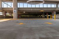 large open parking area with large circular light on top of the roof and yellow painted arrows on the floor