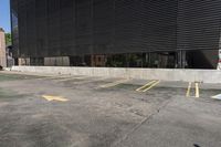 a parking lot in front of a black building with many windows and three yellow arrows