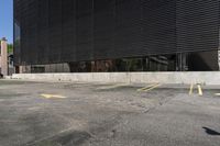 a parking lot in front of a black building with many windows and three yellow arrows