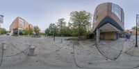 the panorama of a view through the lens of a parking lot with a building and trees in the background