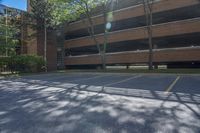 parking lot with parking garage, tree, and building in background and sunlight on street