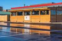 a small, wooden cafe sits on the corner of a parking lot next to a building