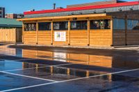 a small, wooden cafe sits on the corner of a parking lot next to a building