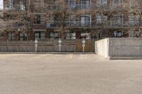 a parking lot with a concrete building in the background and no people sitting on benches on it