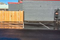 a fire hydrant sitting in the corner of a parking lot next to buildings with a yellow umbrella hanging from the pole