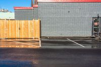 a fire hydrant sitting in the corner of a parking lot next to buildings with a yellow umbrella hanging from the pole