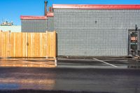 a fire hydrant sitting in the corner of a parking lot next to buildings with a yellow umbrella hanging from the pole