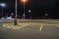 a parking lot at night lit with street lights and an empty parking space in the background