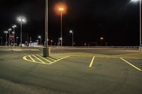 a parking lot at night lit with street lights and an empty parking space in the background