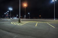 a parking lot at night lit with street lights and an empty parking space in the background