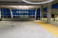 an empty parking garage with no one parked in it at night, with several windows