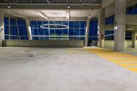 an empty parking garage with no one parked in it at night, with several windows