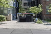 a car driving past an entrance to a building with multiple doors and bushes next to the sidewalk