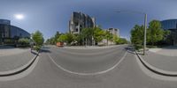 a 360 - view mirror captures an empty street in the middle of the city with buildings