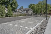 a large parking lot with some trees and rocks in the background in front of the house