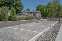 a large parking lot with some trees and rocks in the background in front of the house