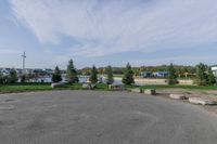 a parking lot in the middle of a residential area with grass and trees in the background